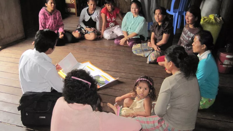 Migrant workers in Cambodia sit on the floor and listen to an official explain about their rights