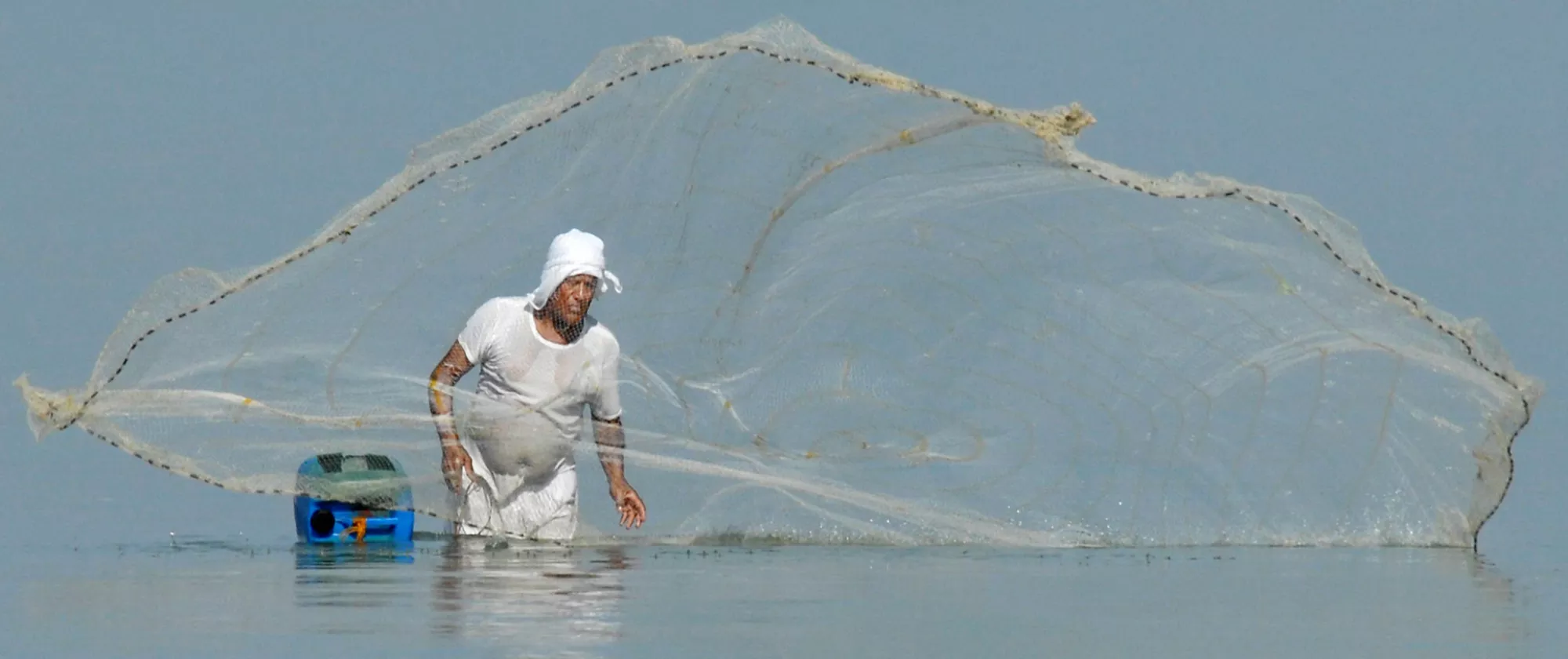 man casting his net in the sea