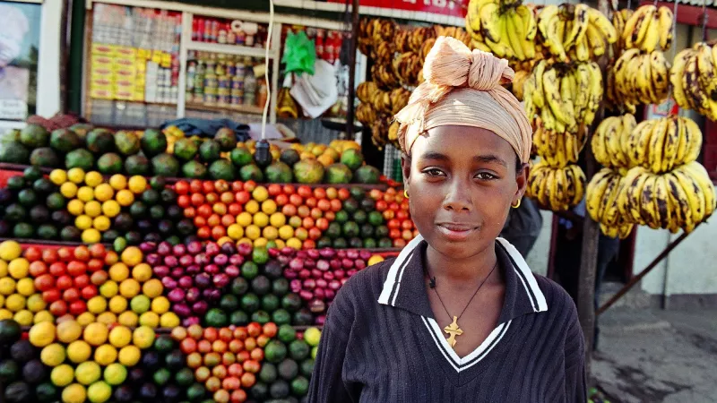 A female fruit seller in front of her fruit stand.