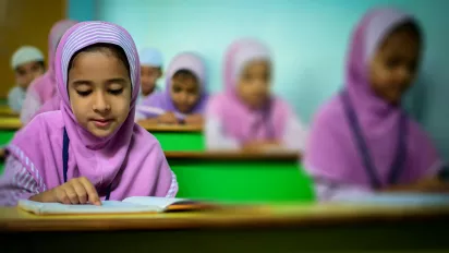 A girl in a classroom reading.