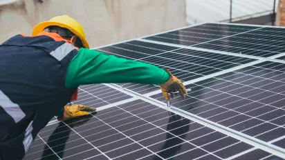 A man installing solar panels on a roof.